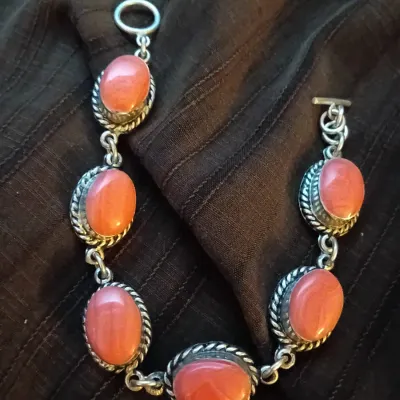 Southwestern-style sterling silver link bracelet featuring oval pink coral cabochons with twisted wire rope borders and a toggle clasp.