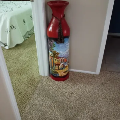 Sale Photo Thumbnail #24: Tall red decorative floor vase featuring a painted Mediterranean village scene and a tasseled rope accent around the neck.