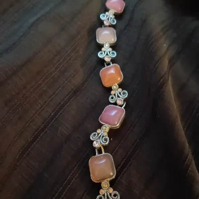 Vintage-style silver-tone link bracelet featuring cushion-cut pink and peach cabochons with filigree scroll accents.