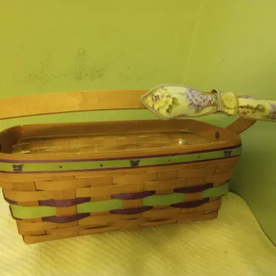 Sale Photo Thumbnail #21: Longaberger woven wood basket with green and purple accents, butterfly charm details, fixed handle, and a plastic liner.
