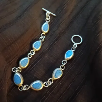 Sterling silver link bracelet featuring tear-drop shaped light blue stones with a toggle clasp closure.