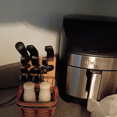 Sale Photo Thumbnail #65: Gourmia stainless steel air fryer sitting next to a wooden knife block set with kitchen shears and salt and pepper shakers.