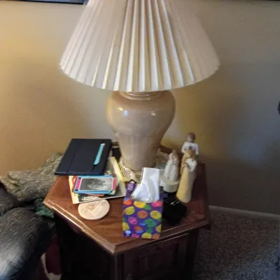 Sale Photo Thumbnail #57: Vintage ceramic table lamp with a pleated fabric shade, set atop a wooden hexagonal end table with storage cabinets below.