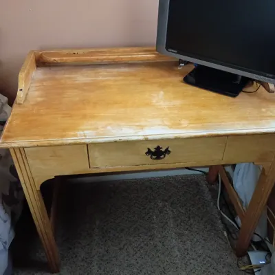 Sale Photo Thumbnail #9: Distressed light wood writing desk featuring a single center drawer with a metal bail pull and a small raised back gallery.