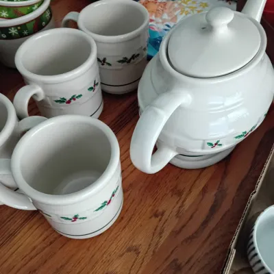 Sale Photo Thumbnail #15: Holiday-themed white ceramic teapot with matching coffee mugs, featuring subtle holly branch motifs and green trim lines.