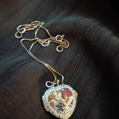 Heart-shaped locket pendant on a fine box chain, featuring floral artwork with colorful gemstone accents and a sparkly border.