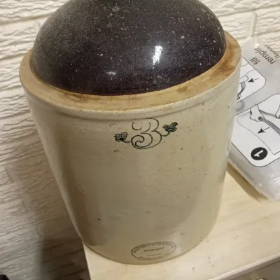 Sale Photo Thumbnail #32: Antique Western Stoneware Company 3-gallon stoneware jug with dark brown glazed top and printed maple leaf graphic.