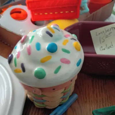Sale Photo Thumbnail #3: Novelty cupcake ceramic container with colorful sprinkles and woven basket base, sitting among assorted small household items.