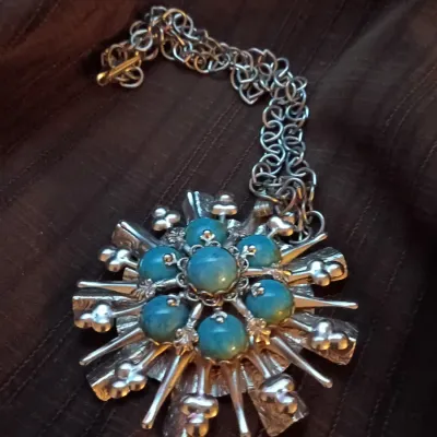 Vintage brutalist silver-tone statement necklace featuring a large starburst pendant set with faux-turquoise cabochons on a heavy chain.