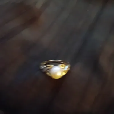 Vintage gold ring featuring a central cultured pearl flanked by decorative leaf-style accents.