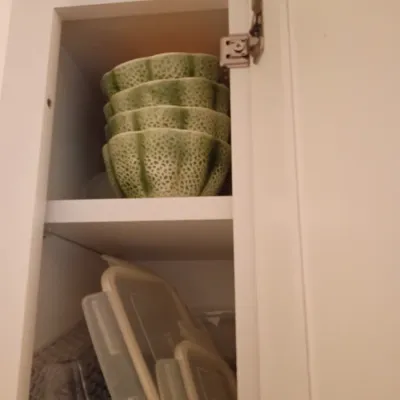 Sale Photo Thumbnail #41: Stack of four green textured ceramic bowls and an assortment of plastic storage containers stored inside a white kitchen cabinet.