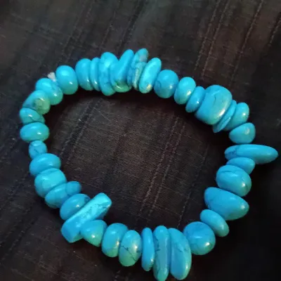 Chunky turquoise chip bead stretch bracelet resting on a dark textured background.
