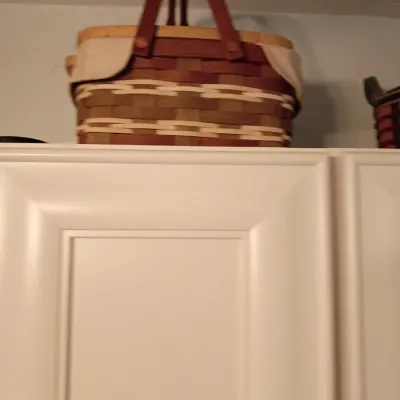 Sale Photo Thumbnail #47: Longaberger-style woven basket with dual leather handles, a light fabric liner, and a wooden band, sitting atop a white cabinet.