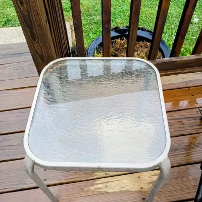 Sale Photo Thumbnail #29: Square outdoor side table featuring a white metal frame and a textured glass tabletop.