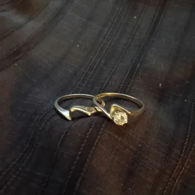Two-piece gold bridal set featuring a bypass-style engagement ring with a round center stone and a matching contoured wedding band.