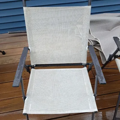 Sale Photo Thumbnail #35: Modern folding patio armchair featuring a black metal frame and light grey mesh sling seat and backrest, showing light surface moisture.