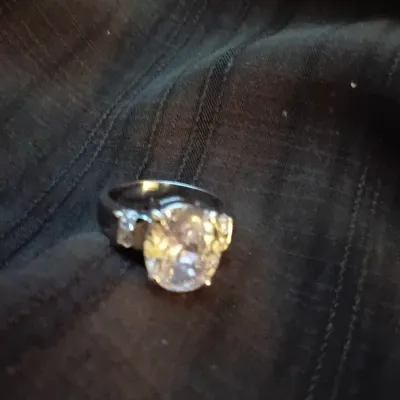 Silver-tone ring featuring a large oval-cut main gemstone flanked by smaller accent stones.