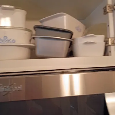Sale Photo Thumbnail #48: Collection of vintage CorningWare pyroceram casserole dishes, including Blue Cornflower pattern pieces, stored inside a white upper kitchen cabinet.