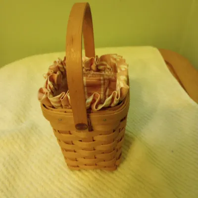 Sale Photo Thumbnail #27: Small Longaberger style woven wood basket with a tall stationary handle and a ruffled fabric liner.