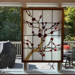 Sale Photo Thumbnail #3: Stained glass window panel featuring a cherry blossom branch design, framed in wood and hanging in front of a window.