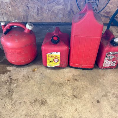 Sale Photo Thumbnail #28: Group of four red plastic gasoline fuel cans in varying shapes and capacities.