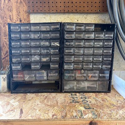 Sale Photo Thumbnail #8: Pair of vintage black metal parts organizers with clear plastic multi-drawer bins, set on a wooden workbench.
