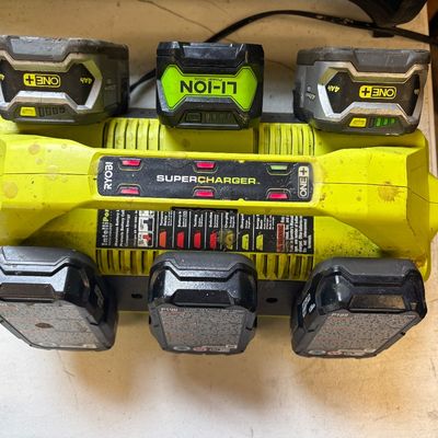 Sale Photo Thumbnail #38: Ryobi ONE+ 18V 6-port Supercharger station loaded with six lithium-ion power tool batteries, showing light cosmetic wear from use.