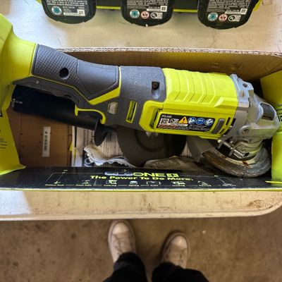 Sale Photo Thumbnail #39: Ryobi One+ 18V cordless angle grinder, model PCL445, shown in its original cardboard box with a grinding wheel attached.