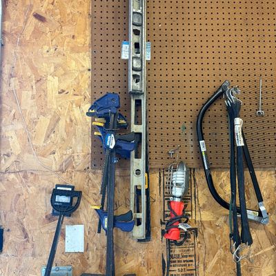 Sale Photo Thumbnail #7: Assorted workshop tools hanging on a pegboard, including Irwin Quick-Grip bar clamps, a long metal level, a work light, and bungee cords.