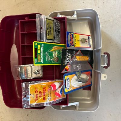 Sale Photo Thumbnail #48: Open plastic tackle box filled with various packaged fishing supplies, including Mepps Aglia lure, Strike King spinnerbait, slip bobbers, and a pocket scale.
