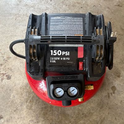 Sale Photo Thumbnail #65: Porter-Cable 6-gallon pancake air compressor, rated at 150 PSI and 2.6 SCFM at 90 PSI, showing some surface wear from use.