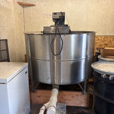 Sale Photo Thumbnail #69: Large stainless steel bulk bee tank or mixing vat with top-mounted motor and PVC drainage plumbing, showing signs of use.