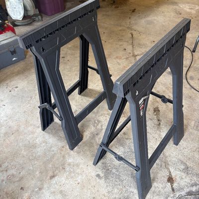 Sale Photo Thumbnail #64: Pair of modern black plastic folding sawhorses in used condition, ideal for workshop or job site use.