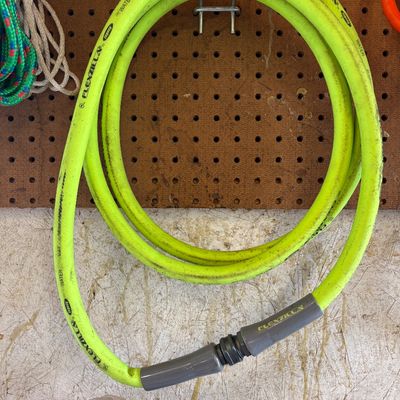 Sale Photo Thumbnail #19: Flexzilla lime green garden hose, showing some light surface wear, hanging on a pegboard hook.