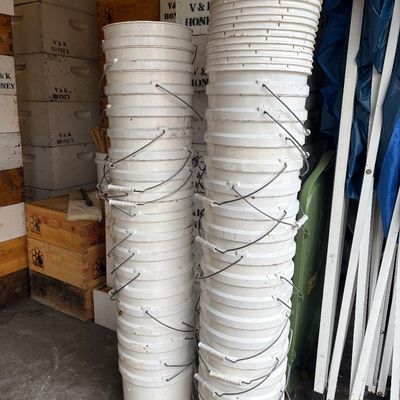 Sale Photo Thumbnail #54: Two tall stacks of white plastic five-gallon utility buckets with metal wire handles.