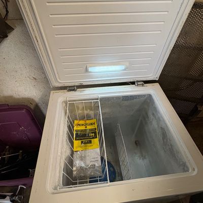 Sale Photo Thumbnail #67: White compact chest freezer shown open, featuring a wire hanging basket with an EnergyGuide tag and interior lighting.