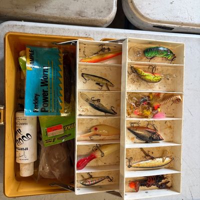 Sale Photo Thumbnail #61: Vintage yellow plastic tackle box loaded with assorted fishing lures, soft baits, and accessories. The collection includes various crankbaits, soft plastic worms, and a bottle of Sportsman's Odor Away.