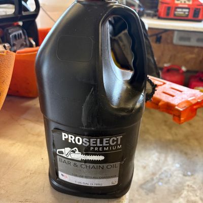 Sale Photo Thumbnail #31: One-gallon jug of ProSelect Premium bar and chain oil for chainsaws, partially used with slight wear on the container.