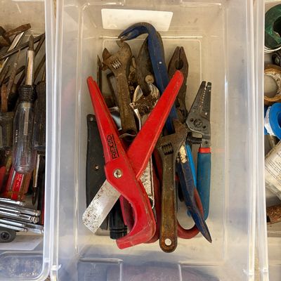 Sale Photo Thumbnail #14: Assorted hand tools in a clear plastic bin, including a red Ridgid plastic pipe cutter, adjustable wrenches, wire strippers, and pliers.