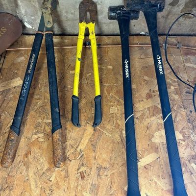 Sale Photo Thumbnail #27: Collection of modern heavy-duty hand tools including two Husky splitting mauls, yellow-handled bolt cutters, and Fiskar tools.