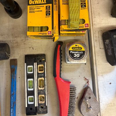 Sale Photo Thumbnail #13: Assortment of hand tools and hardware including DeWalt narrow crown staples, torpedo levels, a Stanley PowerLock 30-foot tape measure, wire brush, chalk line reel, and a Dasco Pro chisel.
