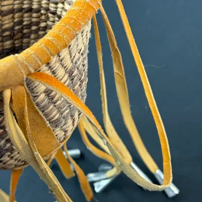 Sale Photo Thumbnail #408: Hand-woven coiled basket featuring yellow suede rim trim and long fringed leather tassels with metal cone tips.
