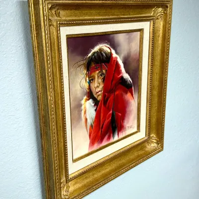 Sale Photo Thumbnail #152: Framed Western oil painting on canvas by Charles Goebel depicting a young Native American child wrapped in a red blanket, set in an ornate gilded wood frame.