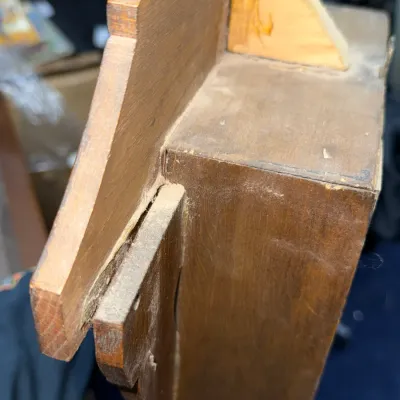 Sale Photo Thumbnail #376: Close-up detail of a vintage wooden wall clock or shelf structure, showing dusty construction joints and a glued triangular support bracket.