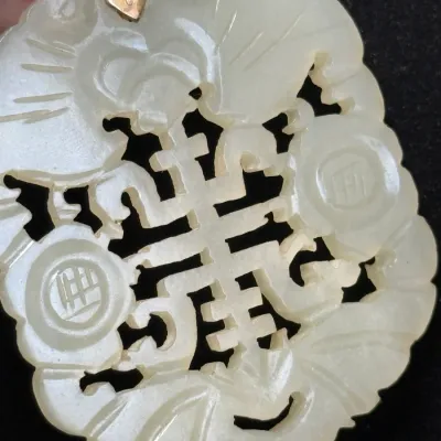 Sale Photo Thumbnail #364: Hand-carved white jade pendant featuring intricate openwork symbols and a gold bail mount.