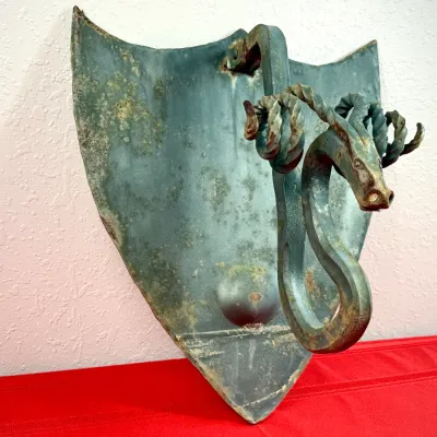 Sale Photo Thumbnail #30: Vintage wrought iron wall sconce featuring a shield-shaped backplate and a detailed dragon or sea serpent mount. The piece shows significant surface patina, verdigris finish, and light corrosion.