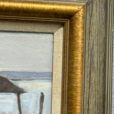 Sale Photo Thumbnail #449: Framed oil painting detailing a rustic seaside scene, enclosed in a multi-tiered gold-toned and weathered wood frame with a linen liner.