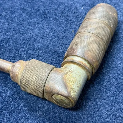 Sale Photo Thumbnail #566: Vintage hand brace drill mechanism showing a knurled metal chuck and selector mechanism with heavy patina.