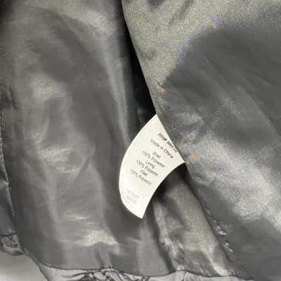 Sale Photo Thumbnail #901: Close-up of a clothing care label inside a gray jacket, detailing 100% polyester materials and RN number 98516.
