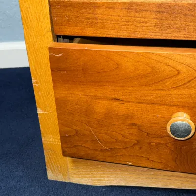 Sale Photo Thumbnail #724: Close-up of a wooden chest of drawers showing surface scratches and finish wear along the side frame and drawer front.